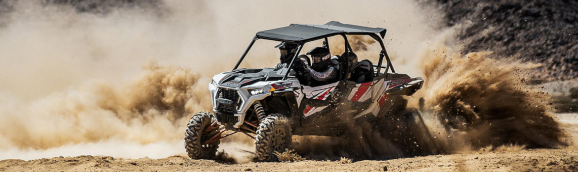 Three occupants taking a sharp turn in a field of dust within a Polaris® RZR XP 4 1000. 